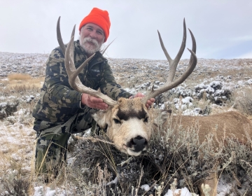 Hunter posing with his Wyoming mule deer in the sagebrush
